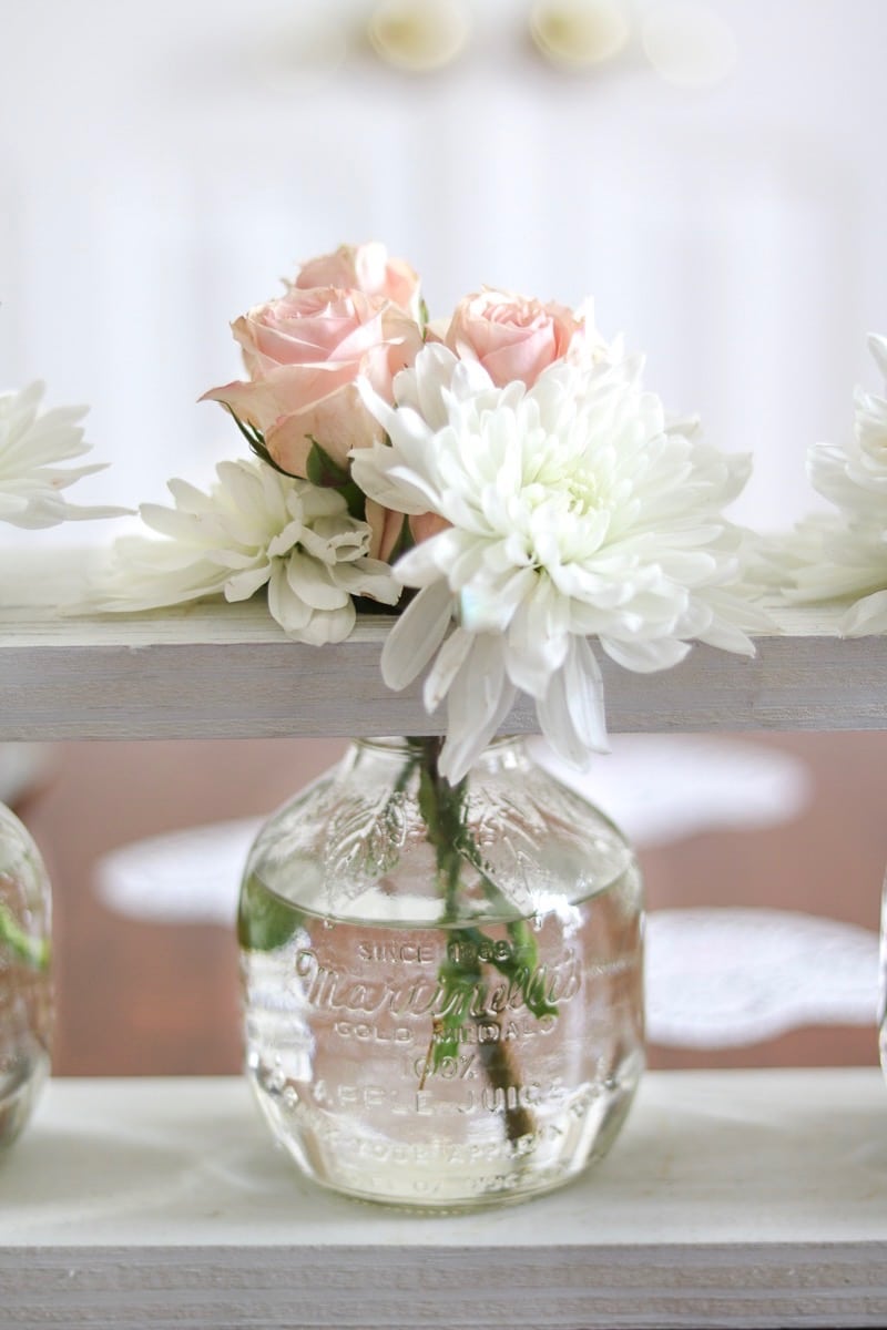 Valentine's table decor idea centerpiece with pink roses and white daisies in a martinelli jar and wooden farmhouse white rustic frame.