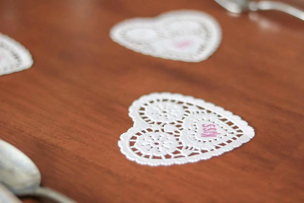 Valentine's table decor idea heart doilies.  Valentine's table decor idea centerpiece with pink roses and white daisies in a martinelli jar and wooden farmhouse white rustic frame.