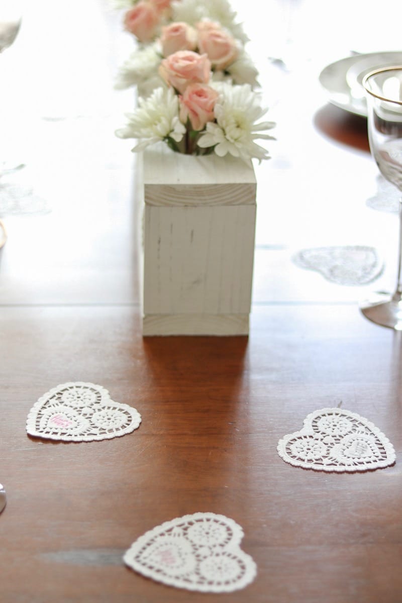 Valentine's table decor idea heart doilies.  Valentine's table decor idea heart doilies.  Valentine's table decor idea centerpiece with pink roses and white daisies in a martinelli jar and wooden farmhouse white rustic frame.