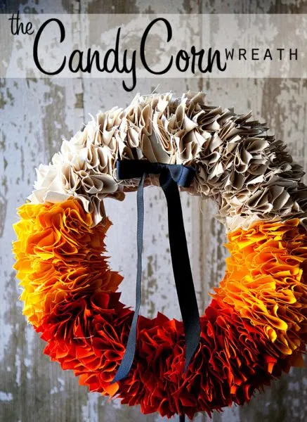 fall wreath ideas in candy corn colors for autumn.  A beautiful wreath made of folded fabrics and arranged from a natural color on top, orange on the sides and a rust red on the bottom then a black grosgrain ribbon bow tucked into the top.  
