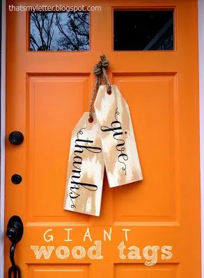 fall wreath ideas give thanks tags.  Large wooden tags hanging on a orange door by knotted ropes. 