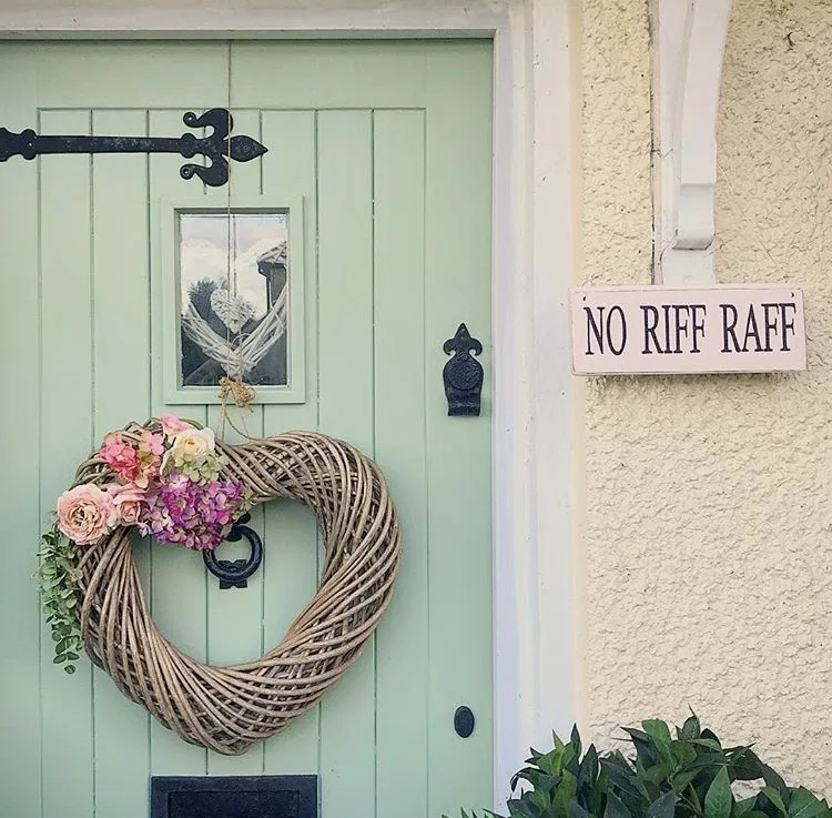 Modern Front Doors by Sugar Print Fairy with a light green front door and a grapevine heart wreath and a wooden sign that reads "no riff raff"