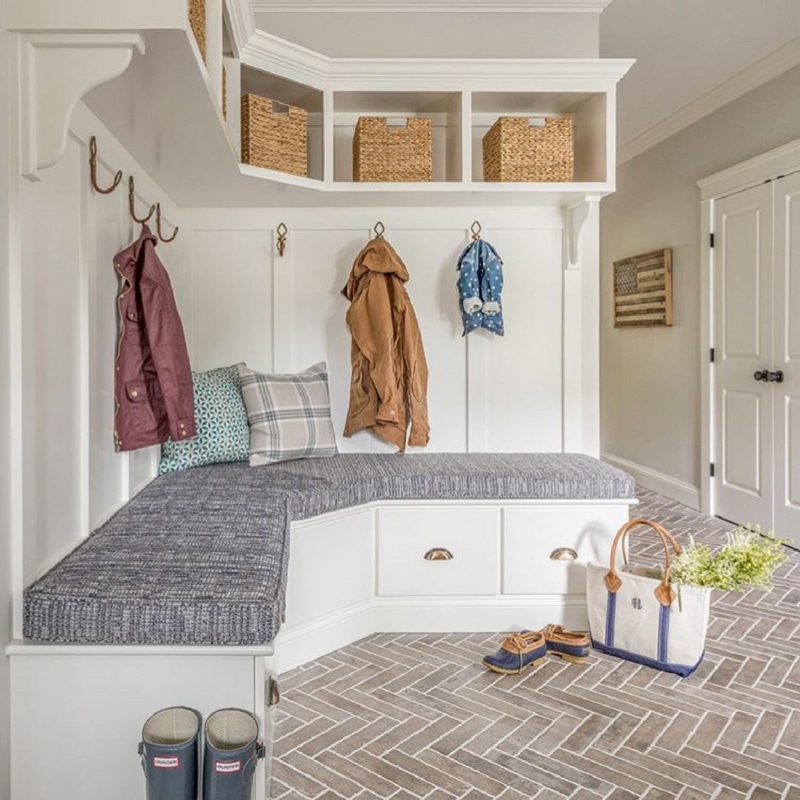 Mudroom Laundry room makeover idea with white build in of basket storage on top, board and batten coat rack wall, bench seat with drawers.