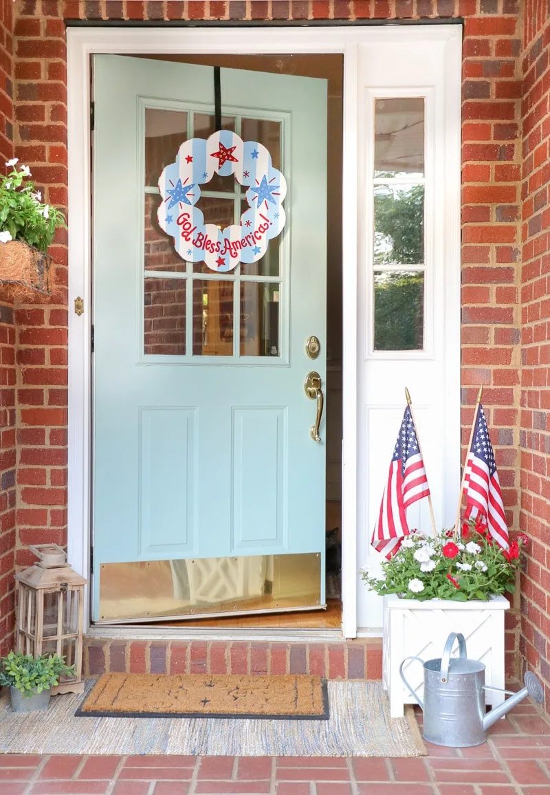 4th of July outdoor decorating ideas on a front porch with a patriotic wreath and stick flags