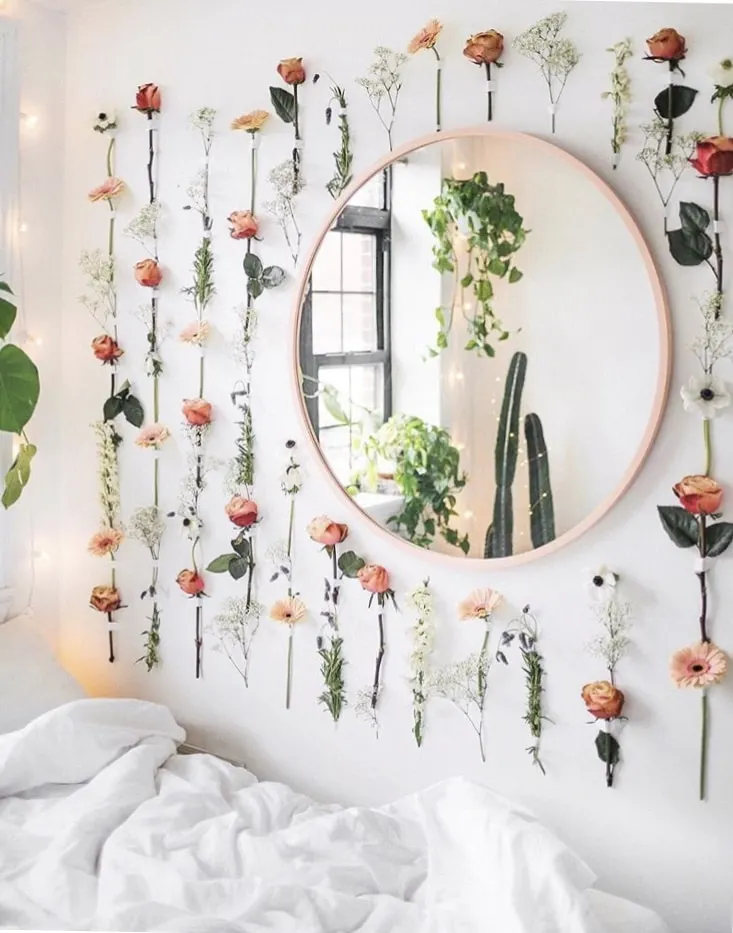 College Dorm Decor Cait Poli picture.  Flowers neatly arranged in rows on the wall around a thin rose gold round mirror.