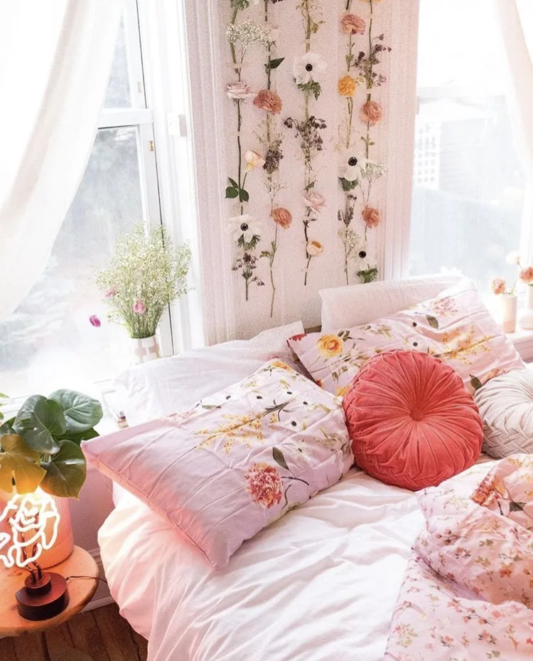 College Dorm Decor Delaney Poli picture.  Flowers hanging on the wall with floral pink bedding, white pulled back curtains and coral round pillow in the middle of the shams.
