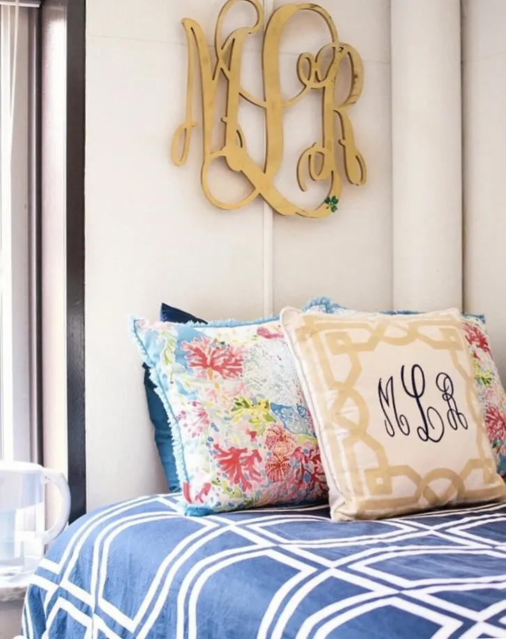 College Dorm Decor Morgan Rose Blog photograph.  Blue and white geometric comforter, Lilly Pulitzer pillow sham, gold and white lattice pattern pillow with monogram.  Gold large monogram on wall above the bed.  Preppy style room.