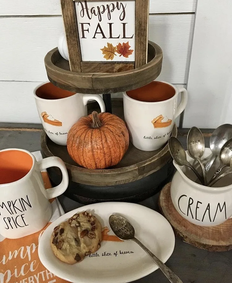 Fall Decor wooden tiered tray coffee station by Grams Farmhouse. This autumn filled tray has two tiers and delicious coffee cups with pumpkin pie on them and an rustic orange pumpkin. With loads of Rae Dunn and topped with a Happy Fall sign.