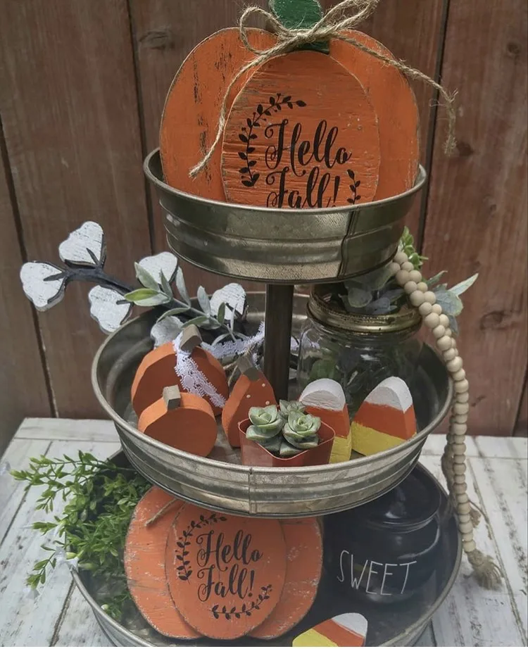 Fall Decor tiered tray by Scissors In Bloom. Her tray is filled with lots of orange colors with wooden pumpkin, candy corn, cotton, plants and a touch of Rae Dunn.