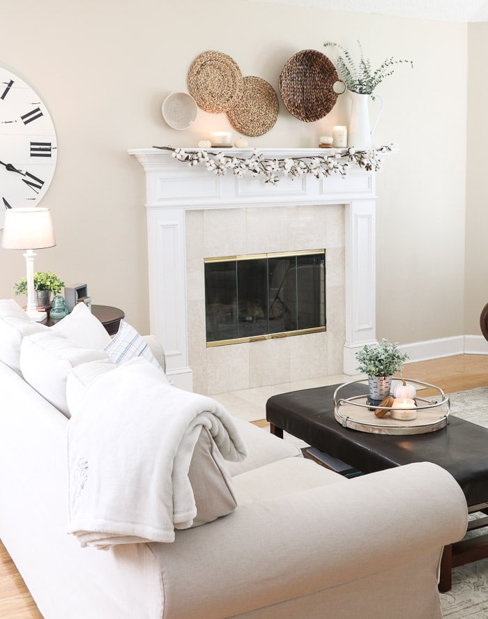 White and neutral fall home decor color scheme with cotton garland mantel and woven baskets.