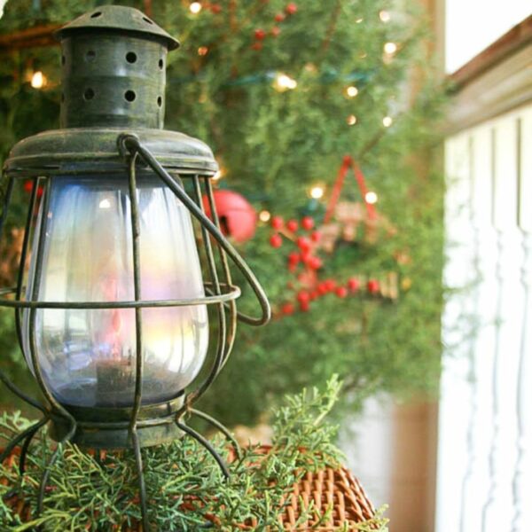 Minimalist primitive Christmas decor ideas of an old antique barn lantern with greenery tucked under it.