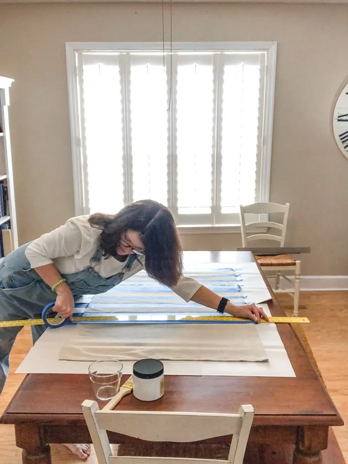 DIY rug using a drop cloth and chalk paint and painters tape to paint stripes