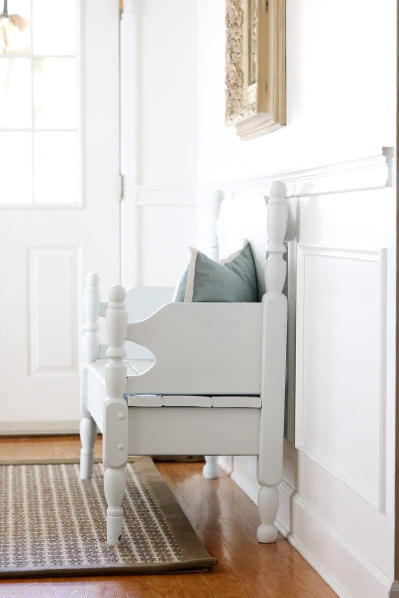 Repurposed bench from old twin bed and painted white and used as a decoration in cottage style home