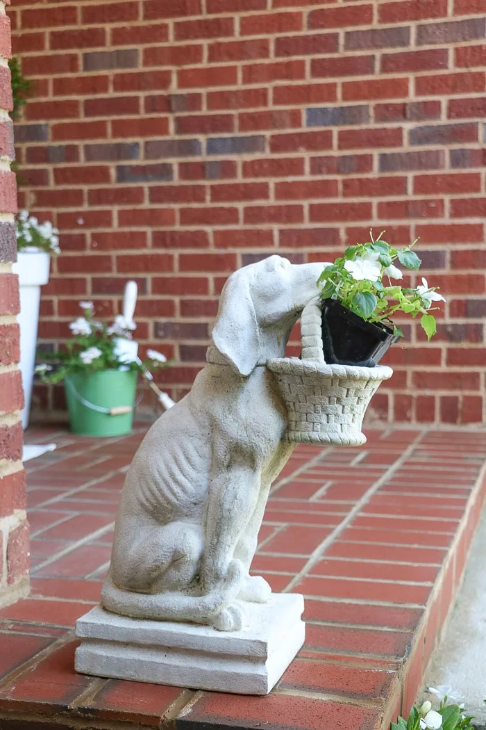 spring porch decorating ideas with dog statue holding a basket of flowers