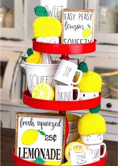 Lemon Décor by Little Cajun House with a red tiered tray filled with Rae Dunn, marshmallow cups, wood signs and lemons