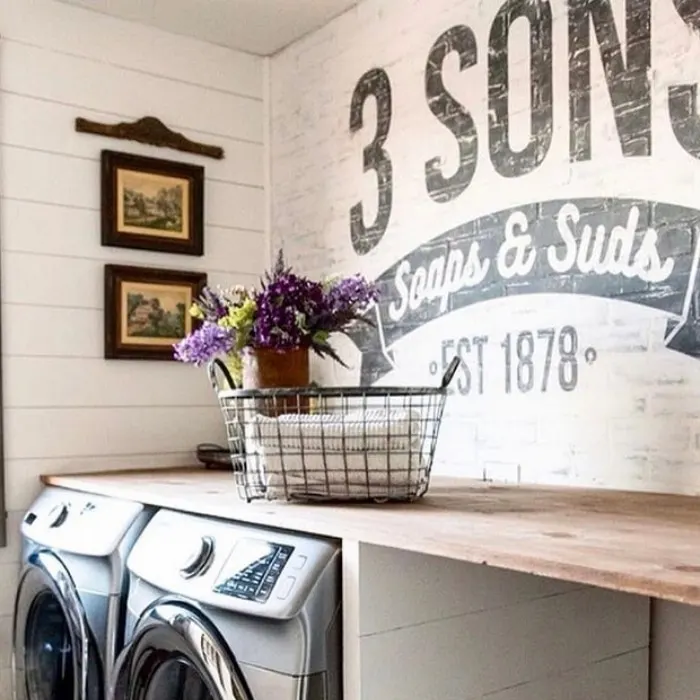 Farmhouse Laundry Room by Three Sons Farmhouse with painted bricks with a logo and a floating shelf