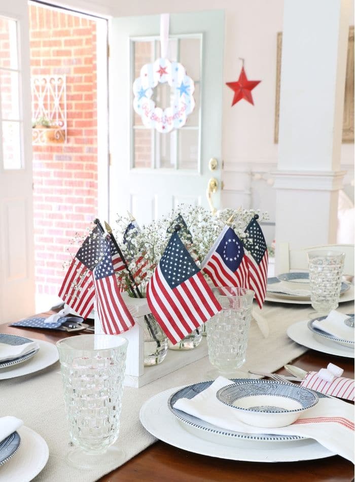 4th of July tablescape with Betsy Ross flags, drop cloth table runner, currier and ives dishes and babies breath 
