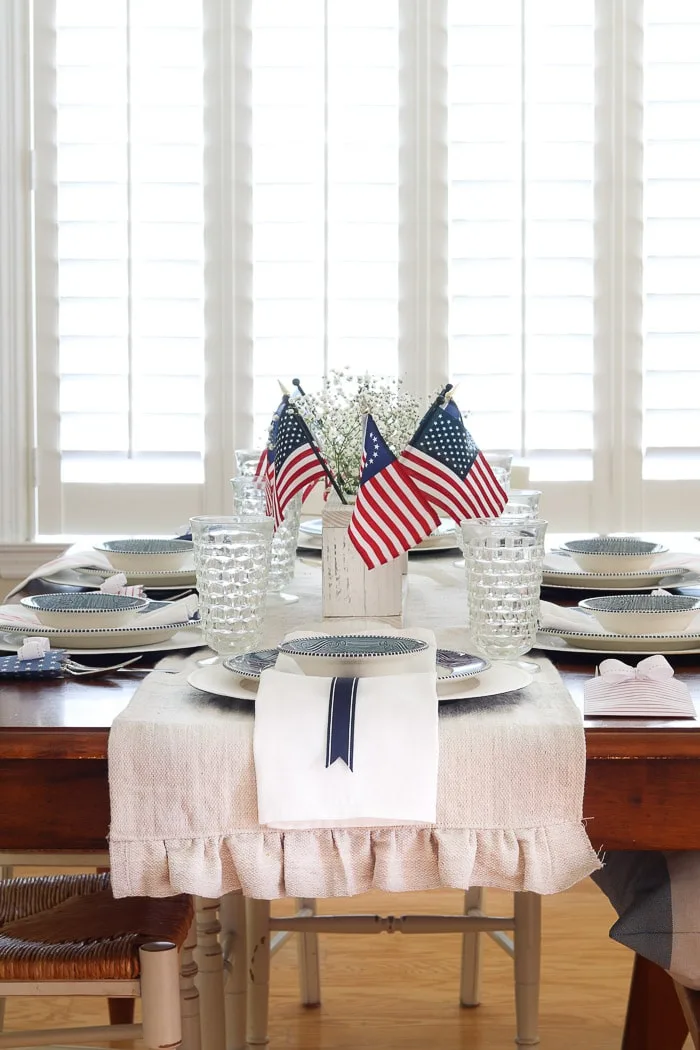4th of July tablescape with Betsy Ross flags, drop cloth table runner and babies breath 