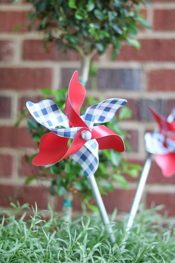 red, white and blue decorations on a small front porch for the 4th of July using a pinwheel