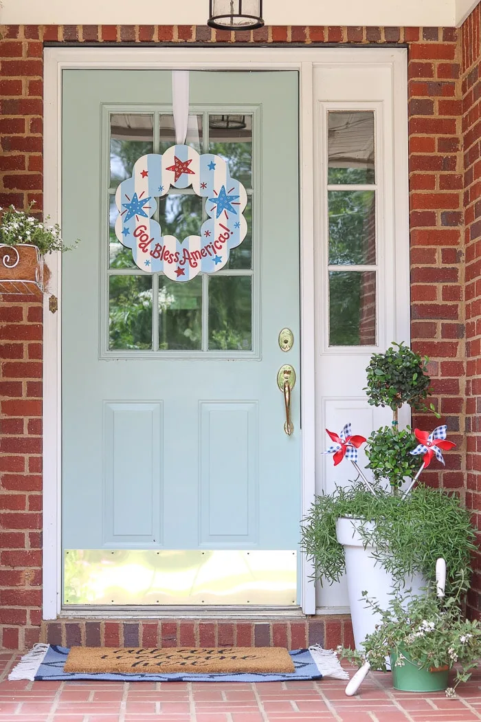 red, white and blue decorations on a small front porch for July 4