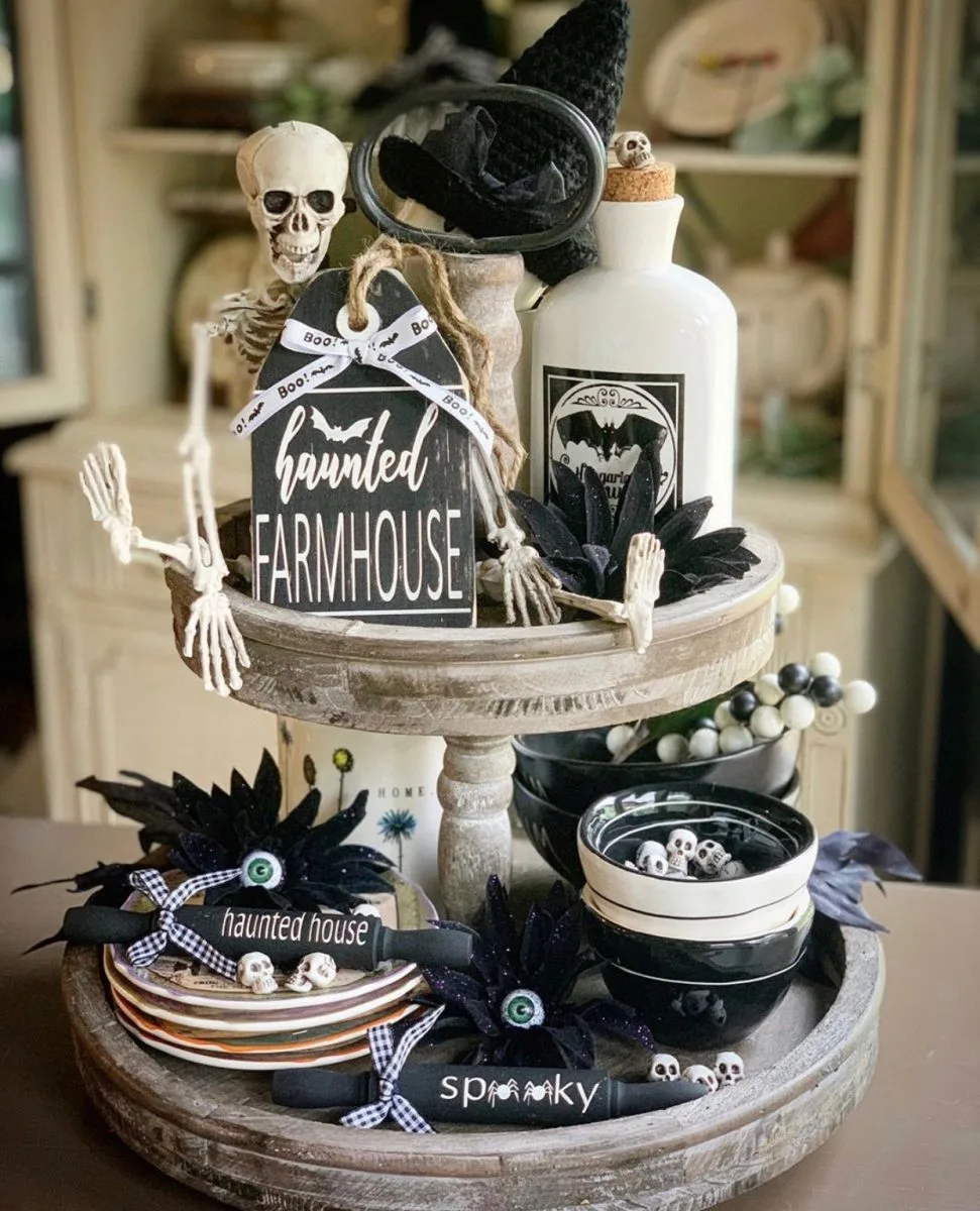 Halloween tiered tray ideas for home.  Skeleton, haunted farmhouse sign, poison bottle, black flowers, heads in bowls, rolling pins on a two tiered tray.