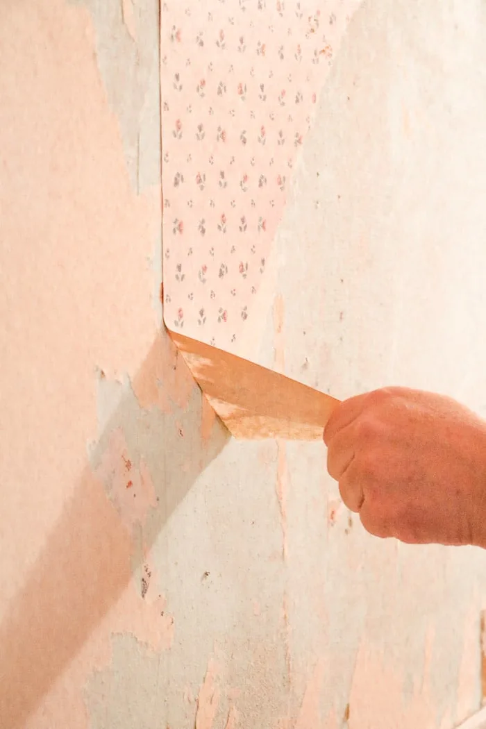 how to remove wallpaper with a steamer.  Removing old wallpaper starting by pulling the top layer of the wallpaper