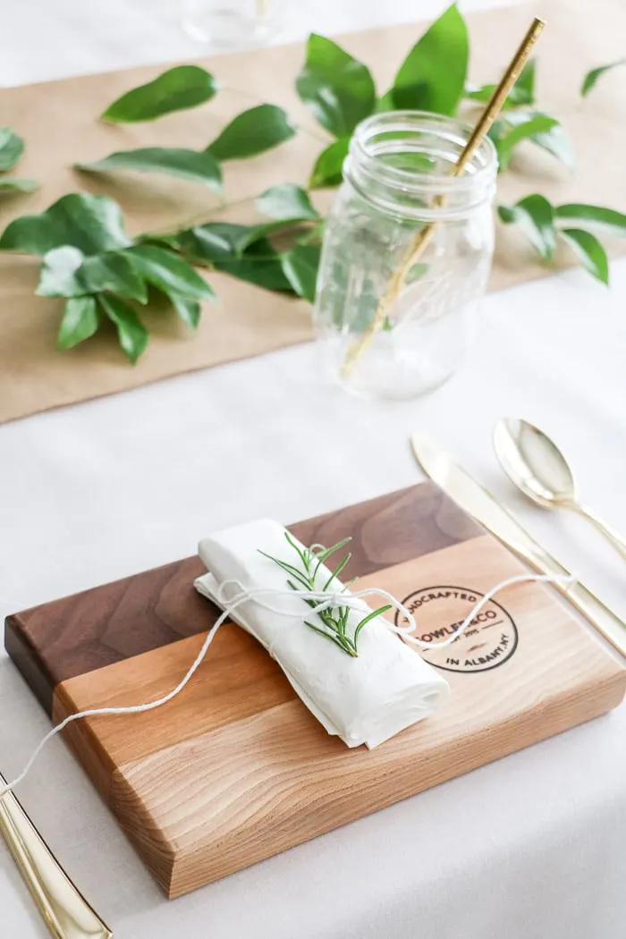 Nurses graduation party ideas that are casual and elegant.  Using Ball mason jars for glasses, cutting boards as plates, rolled napkin with rosemary tucked under twine that is holding the napkin together.  All creates a place setting for each guest.  