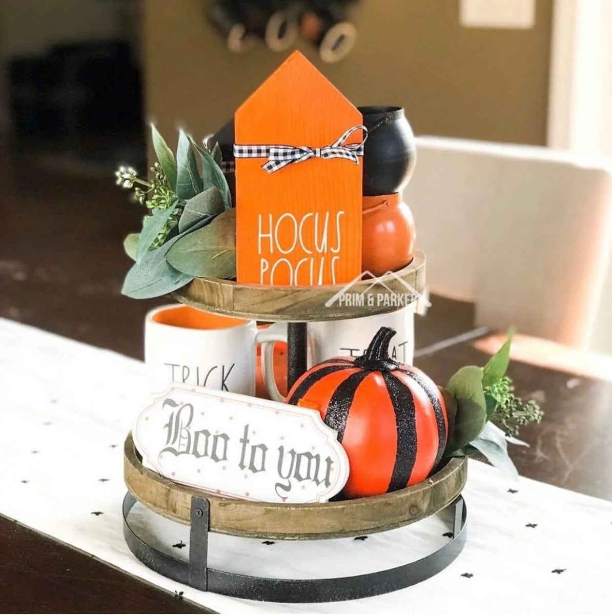 Halloween tiered tray ideas for home.  Orange Hocus Pocus house with black and white gingham ribbon bow, signs, Rae Dunn mug, pumpkin.
