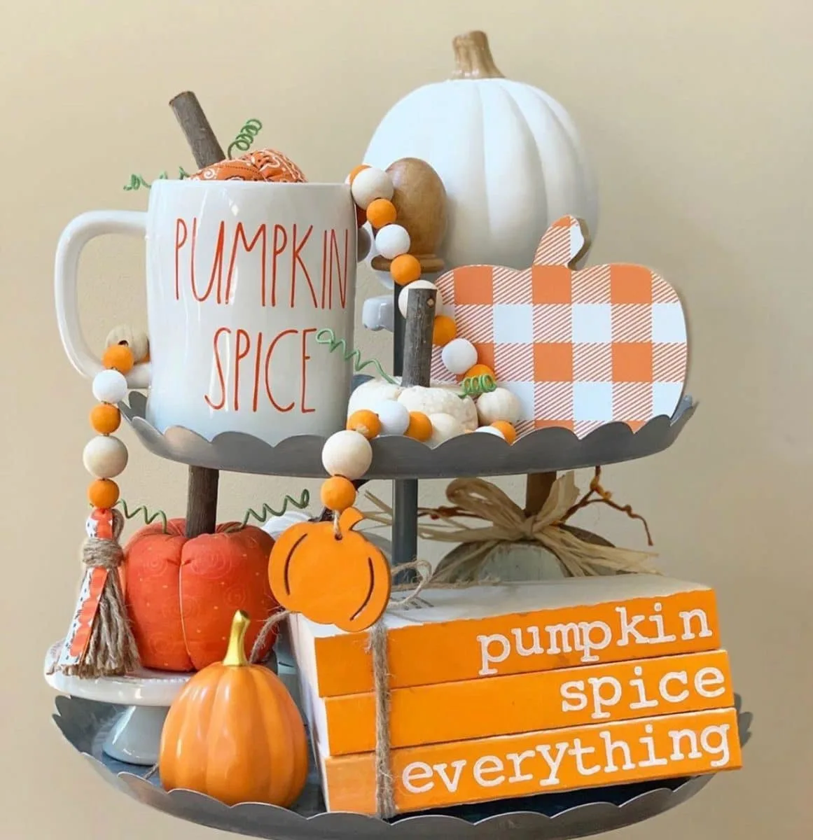 Halloween tiered tray ideas for home.  Orange and white plaid pumpkins, pumpkin spice mug, orange and white wooden beads, pumpkin spice everything wooden books, and two tiered tray