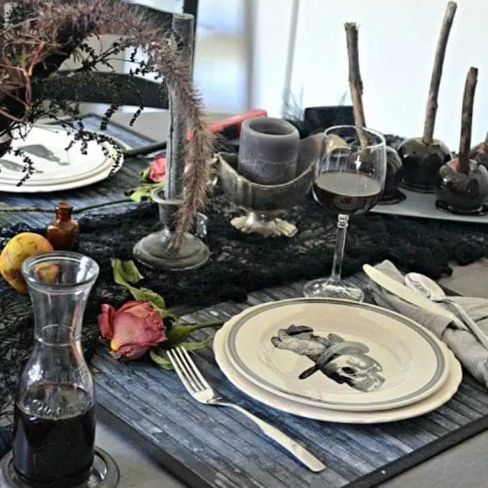 Halloween Table Decorations by Red Cottage Chronicles with skeleton, candles and candy apples as part of the table setting