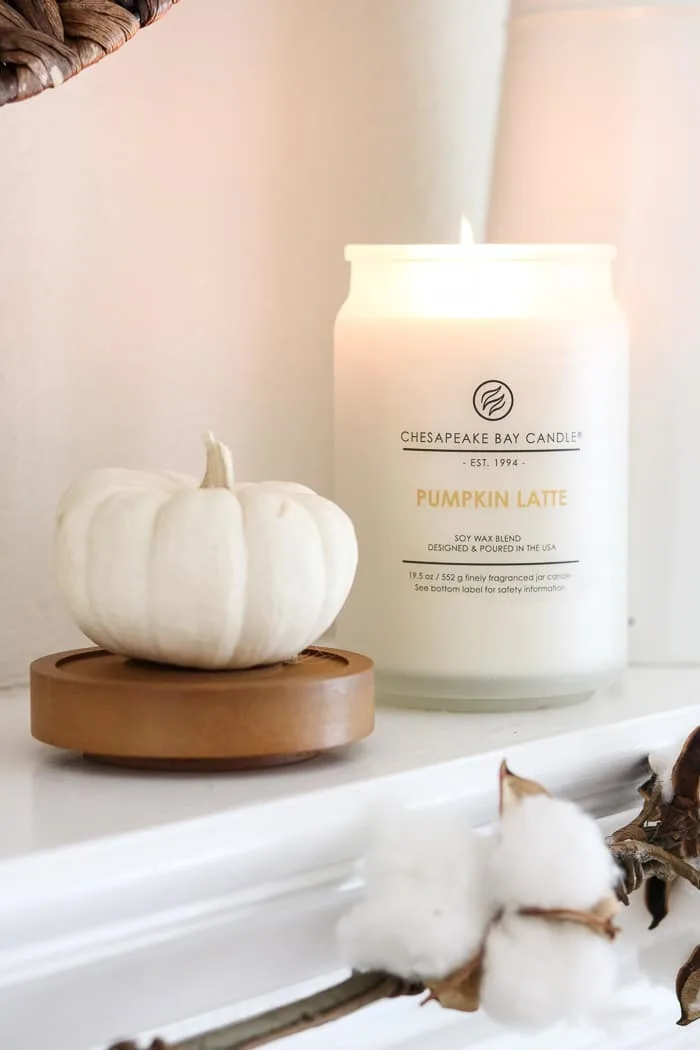 Fall decor on a mantle with a pumpkin latte candle and a white pumpkin.