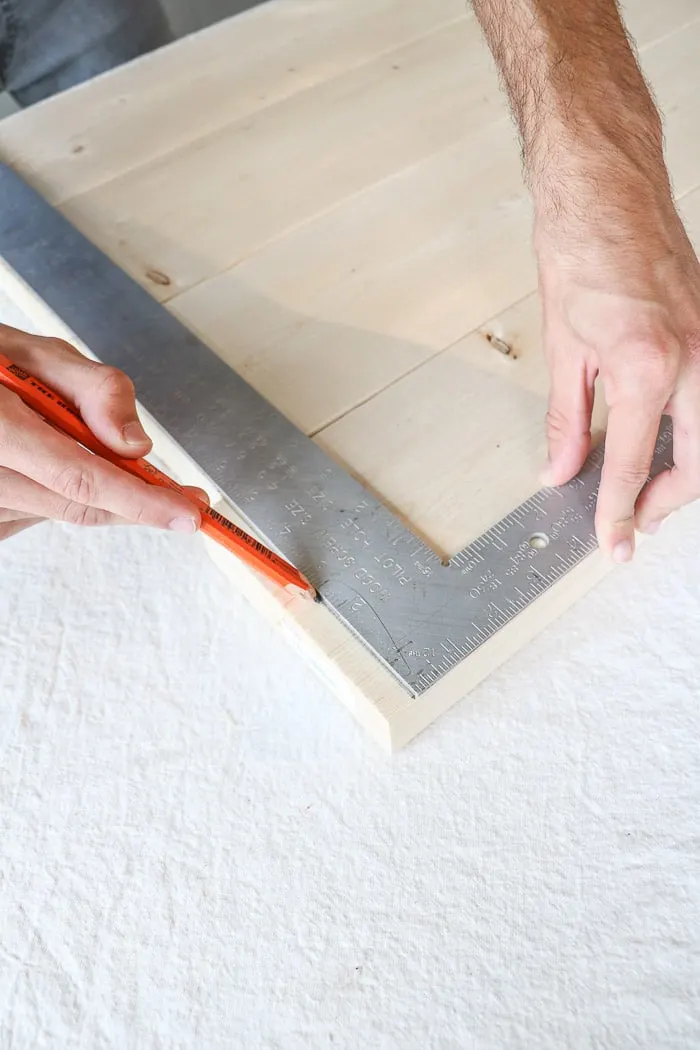 How to build a farmhouse table. Use a L shaped measuring tool to draw a line to cut the boards.
