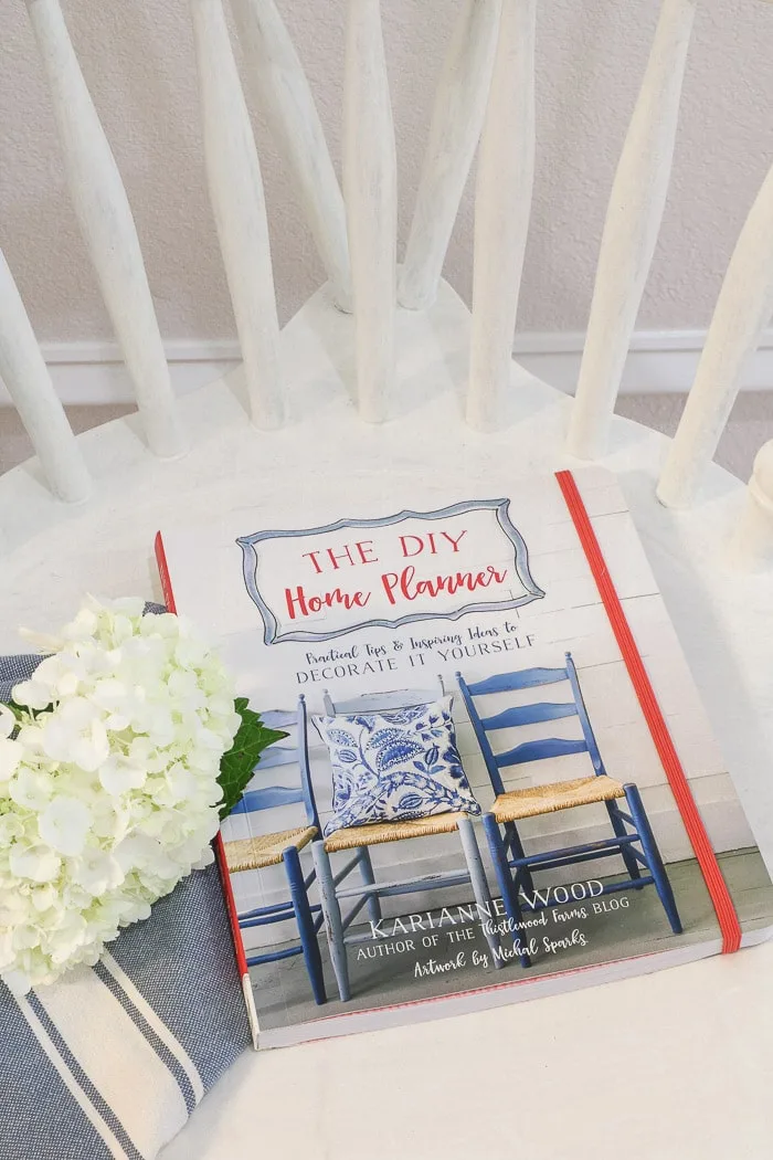 The DIY Home Planner by KariAnne Wood and a magnolia flower.  One of the best interior design books for beginners.