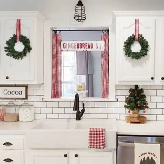 Christmas Kitchen Decor by Our Cozy Cottage with wreaths hanging on cabinets and red and white plaid
