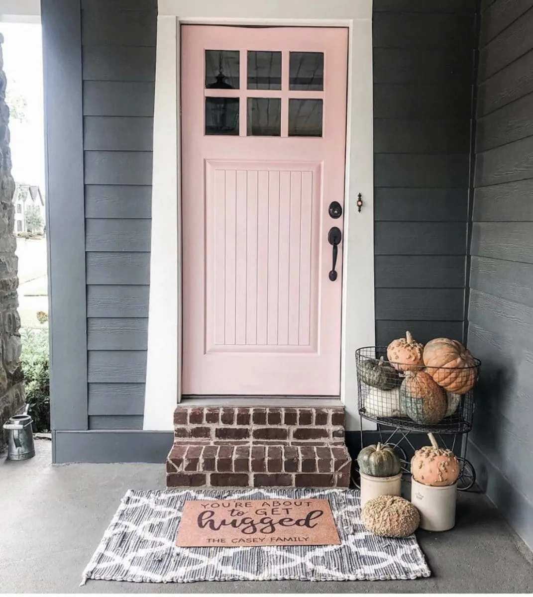 Pink paint color on a modern front door.  Shaker style door in Loveable paint color by Sherwin Williams on a grey house with white trim.
