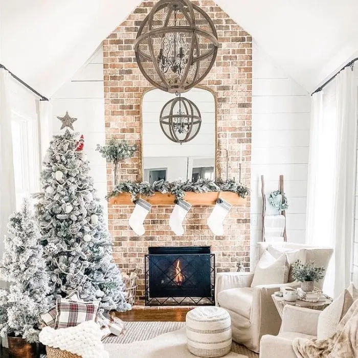 White Christmas Tree Ideas by Between White Houses with a white decorated Christmas tree next to a brick fireplace