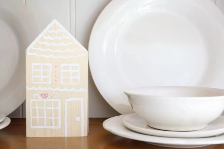 decorate for Valentine with these wooden gingerbread houses nestled between dishes in a hutch