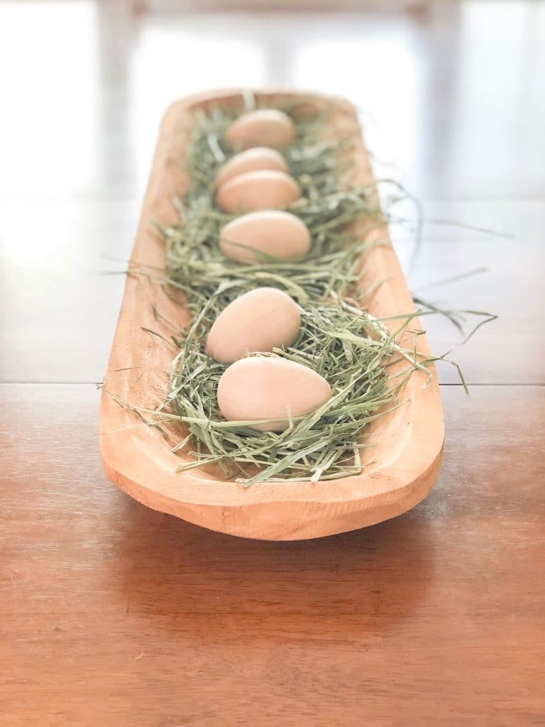 Natural Easter centerpiece of a dough bowl filled with timothy hay and wooden eggs