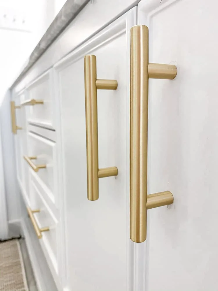 Small farmhouse bathroom remodel using Emtek brushed brass cabinet bar pulls.