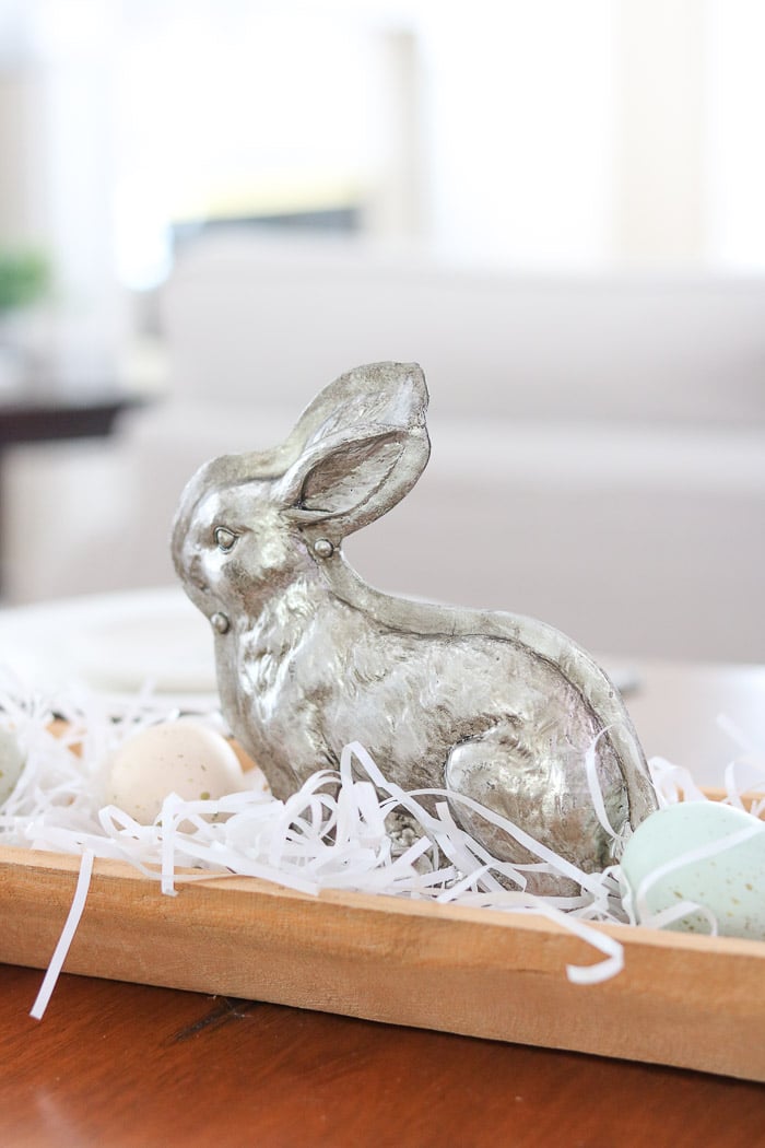 Easter bunny mold nestled inside a dough bowl with white grass and speckled eggs to create a beautiful Easter tablescape.