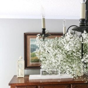 Black chandelier decorated with baby's breath flowers in a dining room.