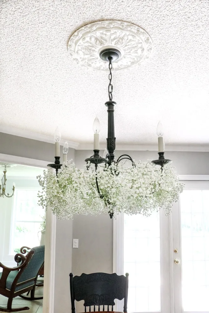Chandelier decorated with baby's breath flowers in a dining room.