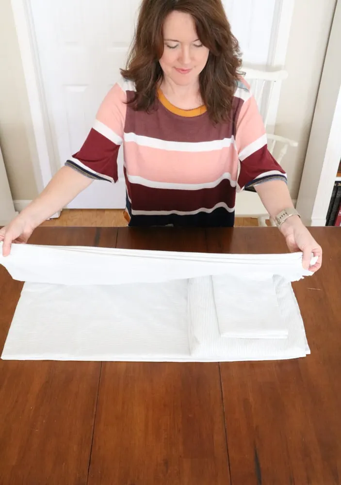 How to fold bed sheets neatly by folding the flat sheet over the fitted sheet and pillowcase.