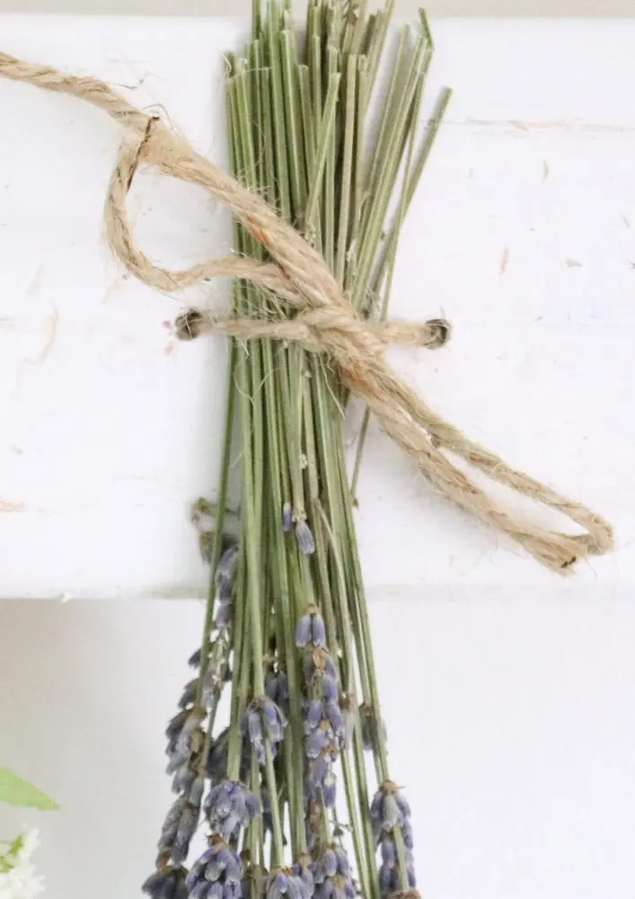 Dried flower wall hanging with lavender tied to a wood board.
