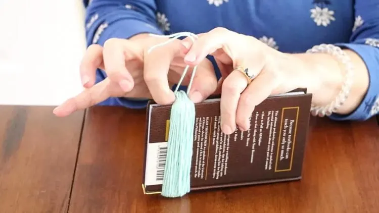 How to make a tassel with yarn by pinching the yarn before tying the 8" piece of yarn.