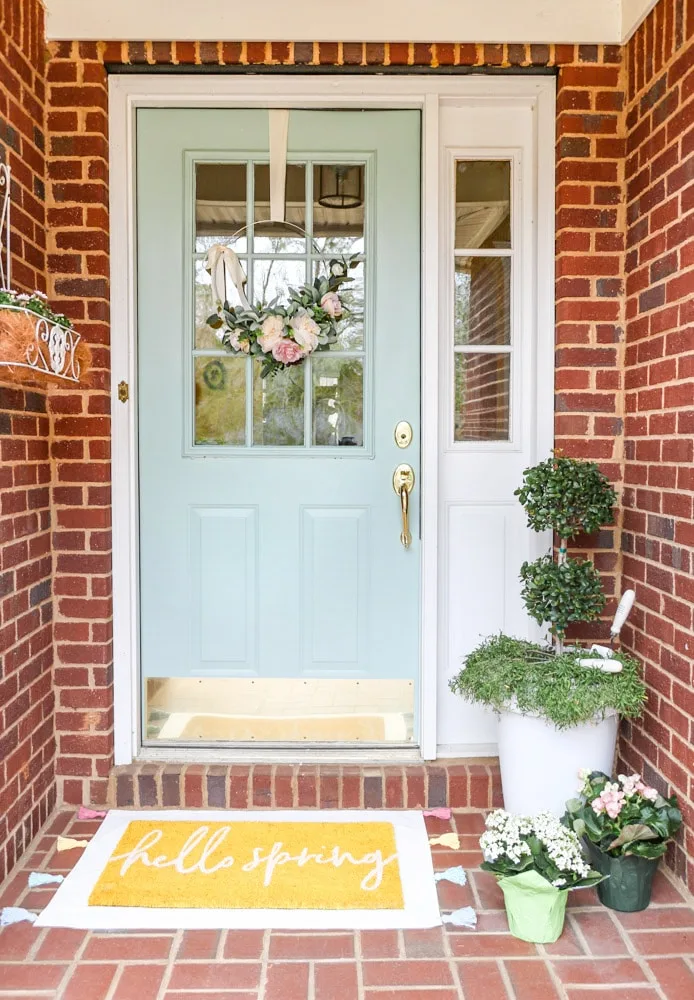 Front porch decorated for spring and a layered rug with a drop cloth rug with tassels