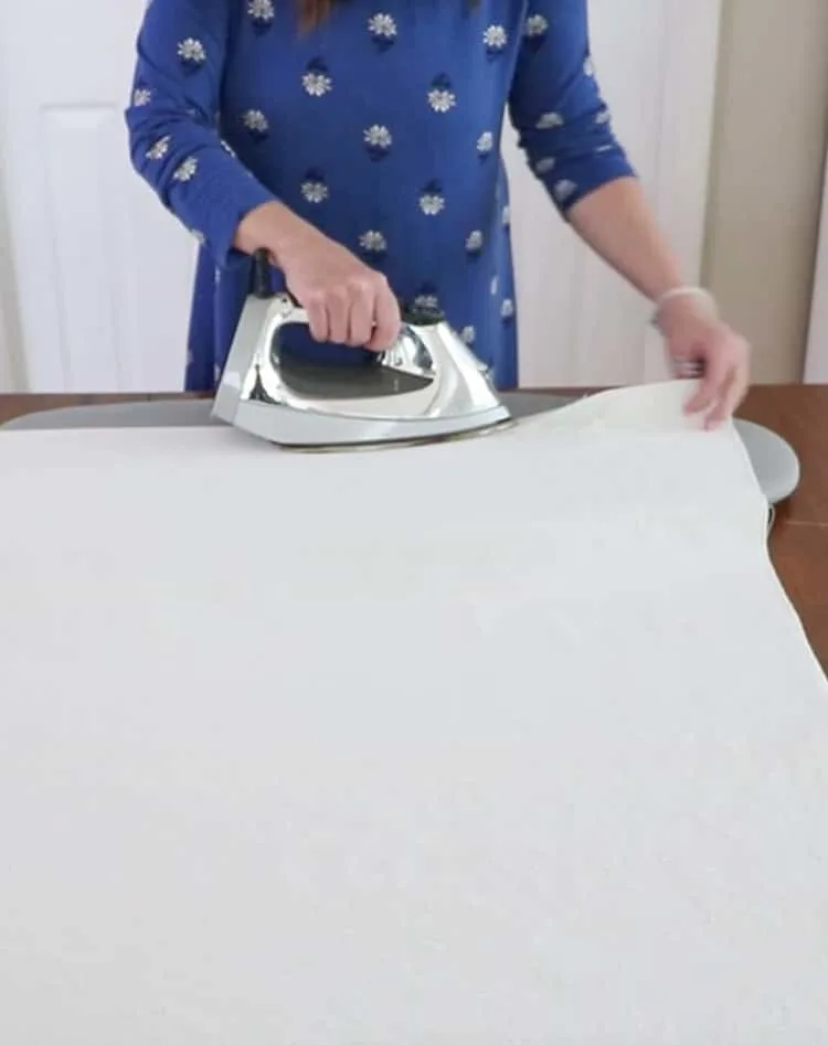 How to make a drop cloth rug by turning the sides under 1" and pressing the canvas.