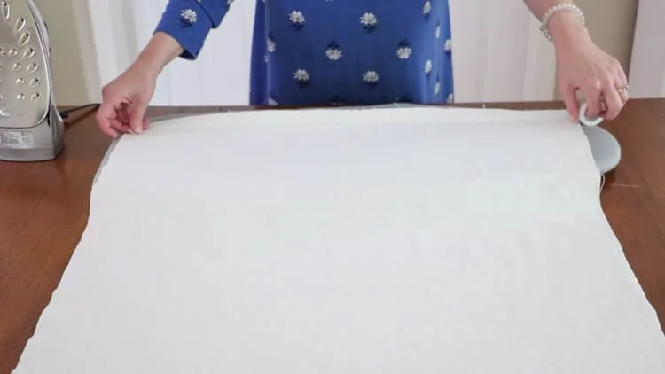 How to make a drop cloth rug by opening the folded canvas and measuring out a piece of no sew hem tape and cutting it to the length.