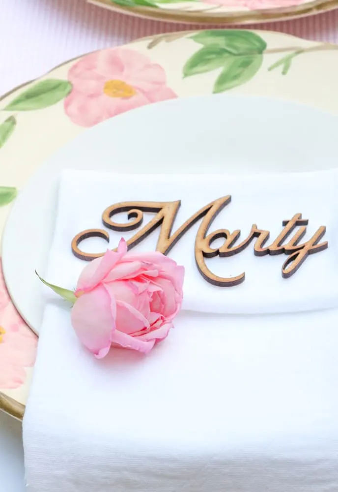 Garden party place setting idea with a pink rose on a white linen napkin sitting on a desert rose place and a white salad plate.