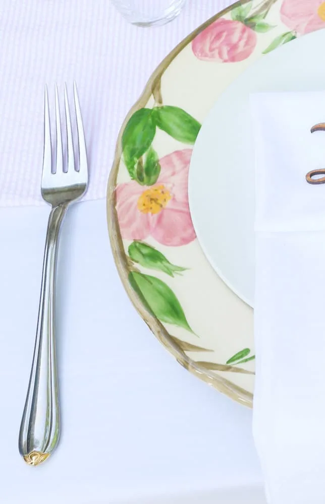 Garden party decoration ideas using white linen tablecloth, pink and white runner and desert rose dishes with a white salad plate in the middle.  Then add silverware.